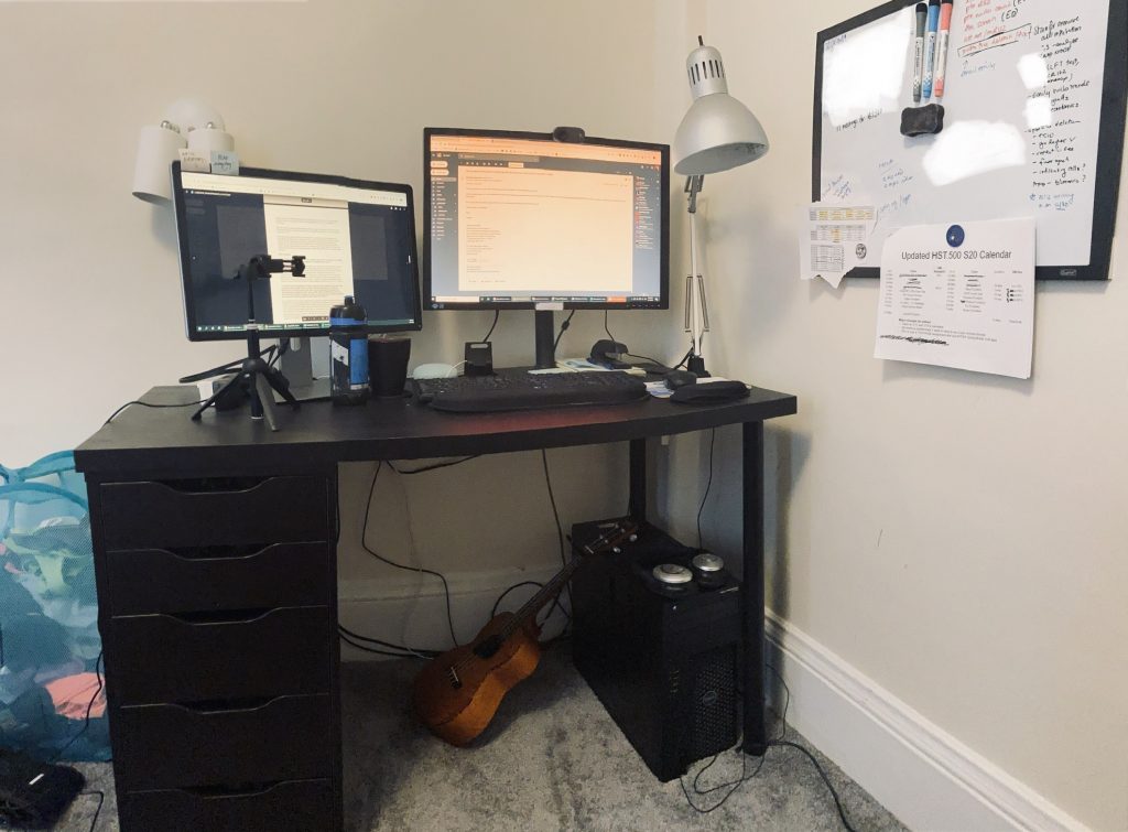 desk with two monitors and a ukulele