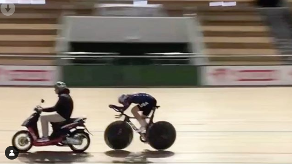 picture of a biker on a velodrome chasing a moped